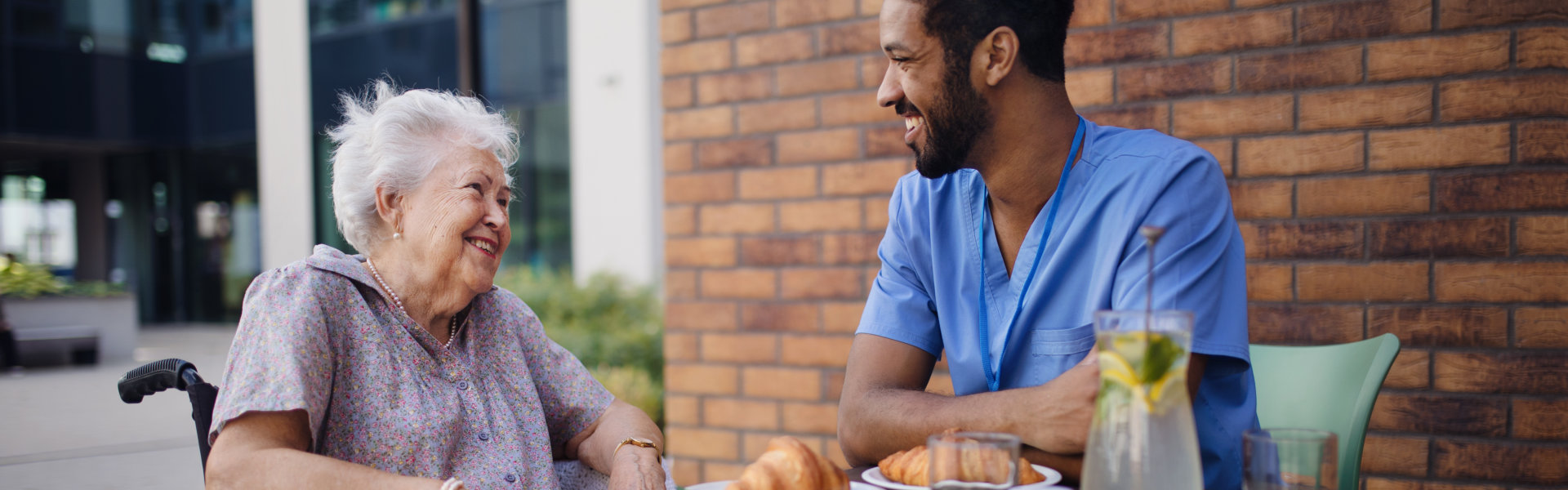 Male aide and elder woman are talking outside the house